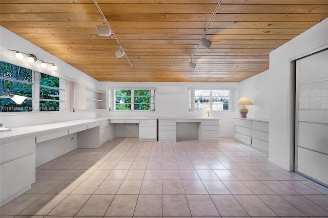 unfurnished office featuring built in desk, track lighting, and a wealth of natural light