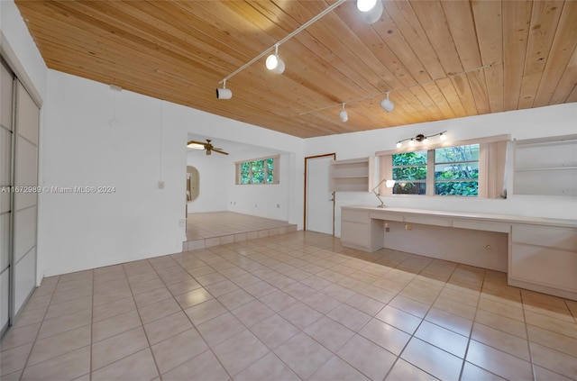 unfurnished living room featuring built in desk, wooden ceiling, light tile patterned flooring, and rail lighting