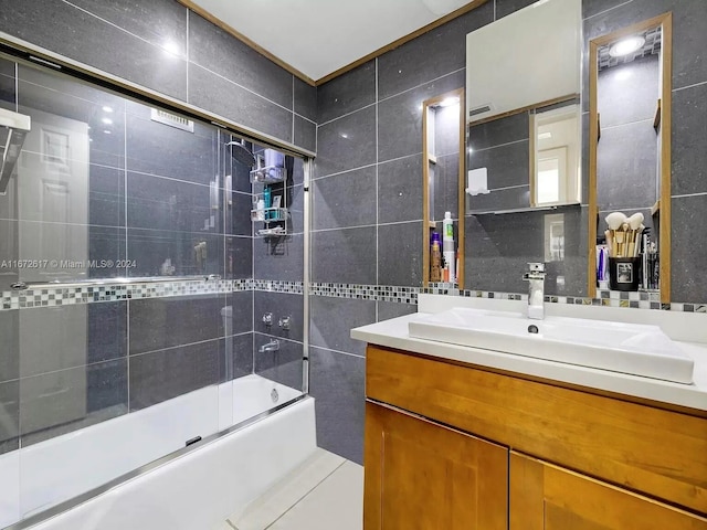 bathroom with shower / bath combination with glass door, vanity, and tile walls