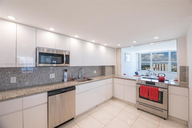 kitchen with decorative backsplash, stainless steel appliances, sink, light tile patterned floors, and white cabinets