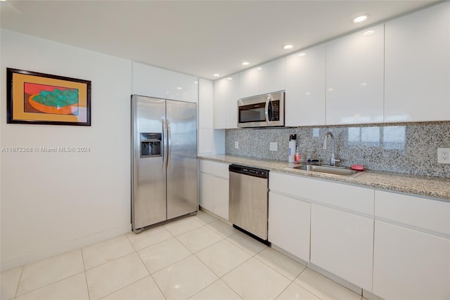 kitchen featuring appliances with stainless steel finishes, tasteful backsplash, sink, light tile patterned floors, and white cabinets