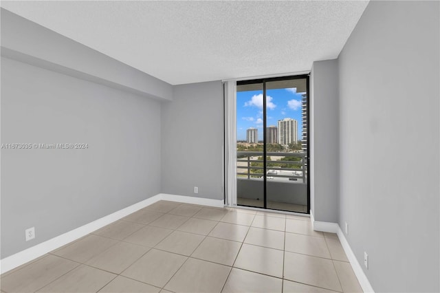 tiled empty room featuring floor to ceiling windows and a textured ceiling