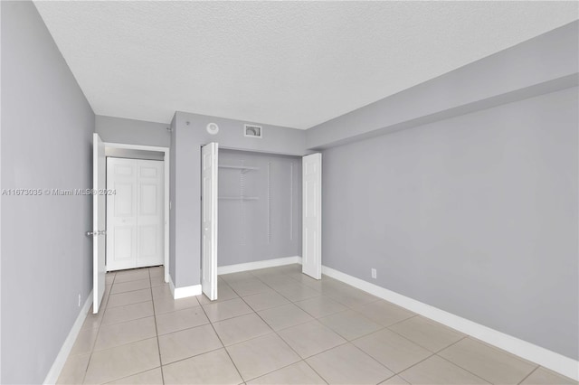 unfurnished bedroom with a textured ceiling, a closet, and light tile patterned floors