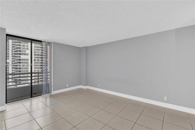 spare room featuring a textured ceiling and light tile patterned floors