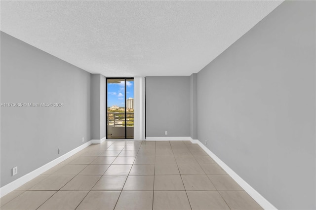 unfurnished room featuring floor to ceiling windows, a textured ceiling, and light tile patterned flooring