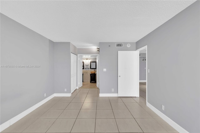 tiled empty room with a textured ceiling