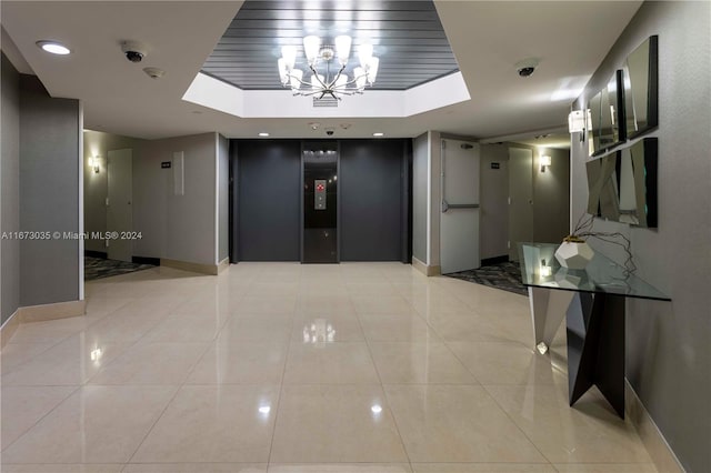 corridor featuring a raised ceiling, light tile patterned floors, and elevator