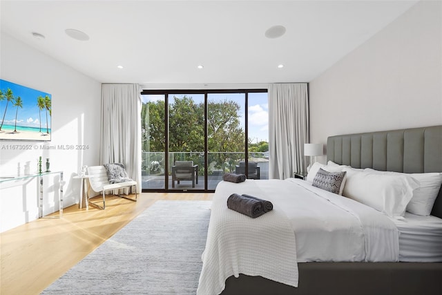 bedroom with wood-type flooring, floor to ceiling windows, and access to exterior