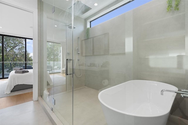 bathroom featuring shower with separate bathtub, a wealth of natural light, and hardwood / wood-style flooring