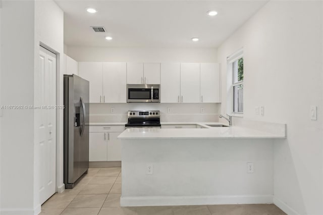 kitchen with kitchen peninsula, stainless steel appliances, and white cabinetry