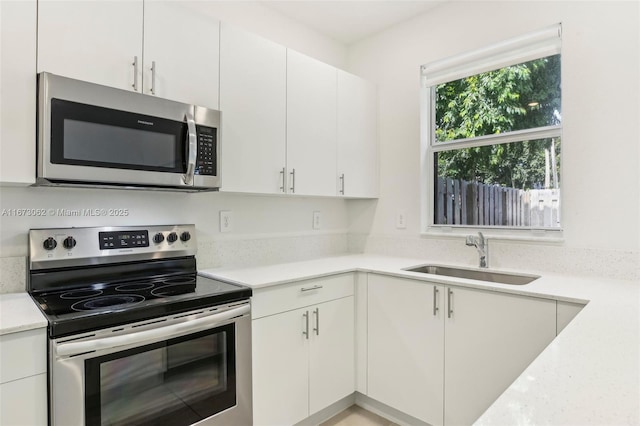 kitchen featuring appliances with stainless steel finishes, sink, and white cabinetry