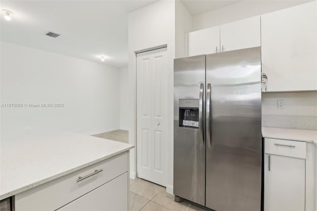 kitchen featuring stainless steel refrigerator with ice dispenser, light stone counters, white cabinets, and light tile patterned flooring