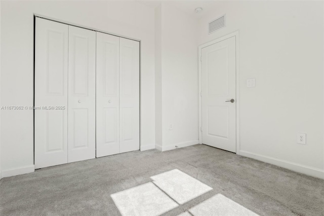 unfurnished bedroom featuring a closet and light colored carpet