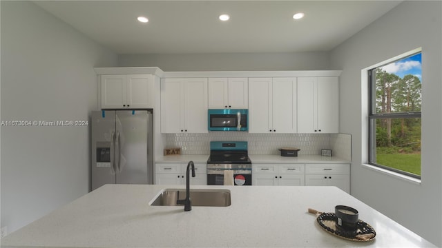 kitchen featuring white cabinetry, tasteful backsplash, appliances with stainless steel finishes, and sink