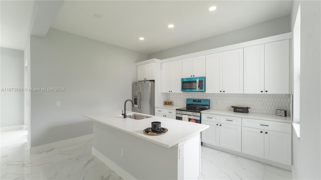 kitchen featuring a kitchen island with sink, stainless steel appliances, backsplash, sink, and white cabinets