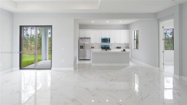 kitchen with white cabinetry, a healthy amount of sunlight, stainless steel appliances, and a center island with sink