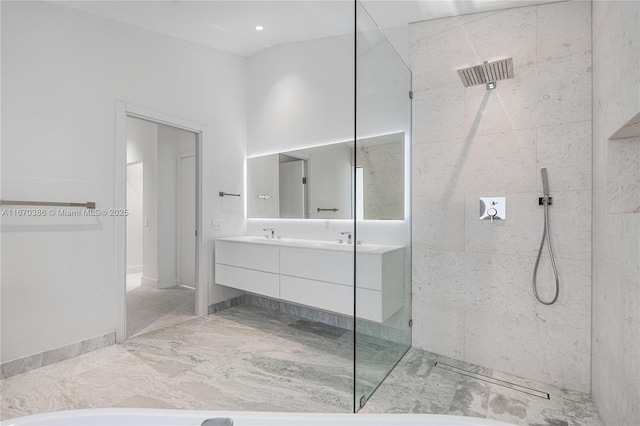 bathroom with a tile shower and vanity