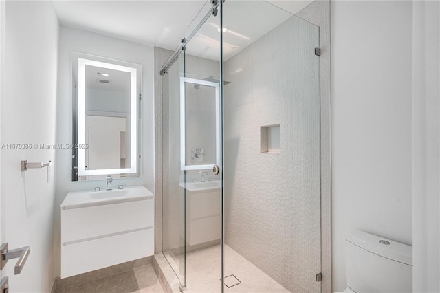 bathroom with tile patterned floors, vanity, toilet, and a shower with door