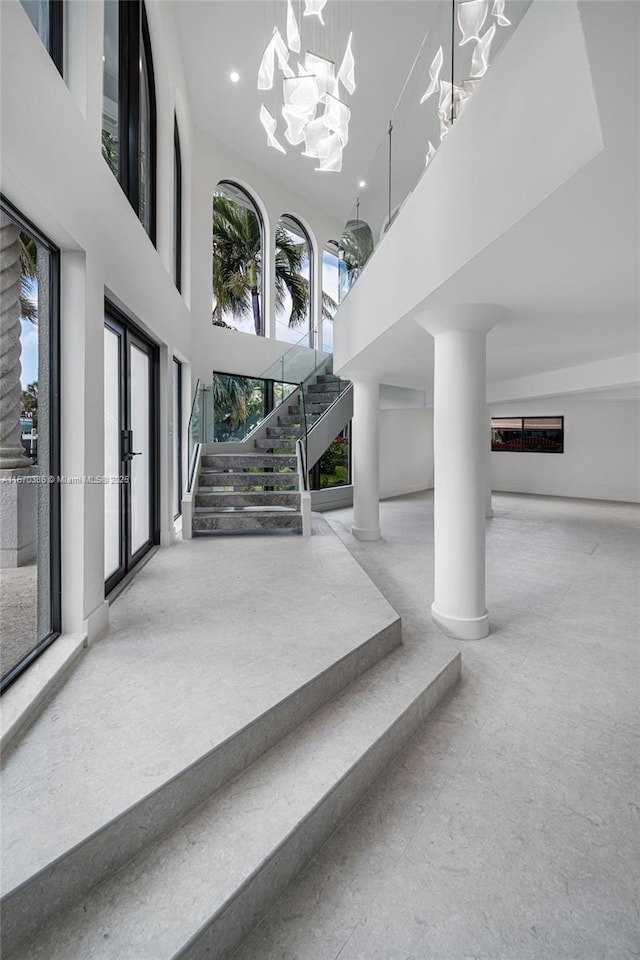 interior space with a high ceiling, an inviting chandelier, and french doors