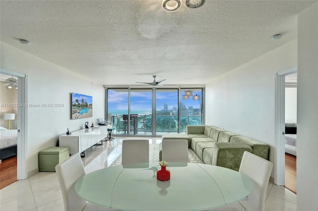 tiled dining area featuring ceiling fan, a textured ceiling, and floor to ceiling windows