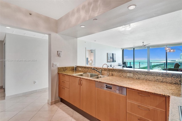 kitchen with light tile patterned flooring, light stone countertops, sink, and stainless steel dishwasher