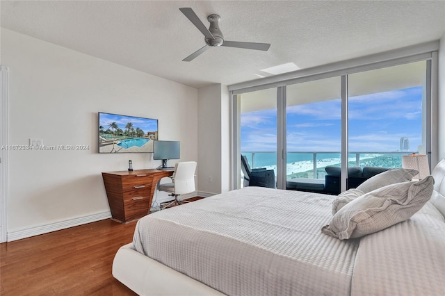 bedroom with access to outside, a textured ceiling, ceiling fan, floor to ceiling windows, and dark hardwood / wood-style floors