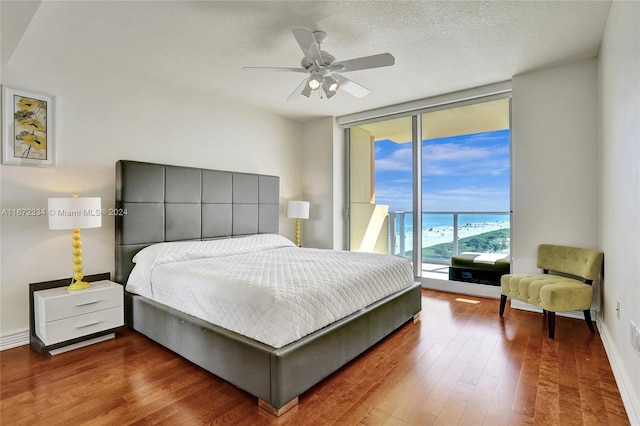 bedroom featuring dark hardwood / wood-style flooring, access to outside, a textured ceiling, and ceiling fan