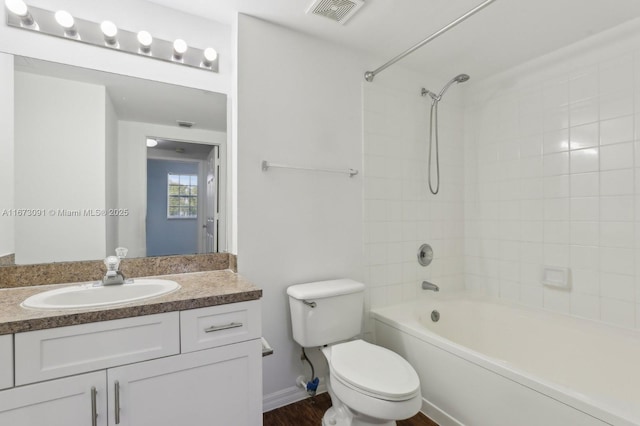 full bathroom featuring vanity, tiled shower / bath combo, and toilet