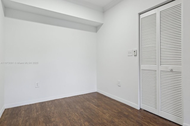 interior space with dark hardwood / wood-style flooring, ornamental molding, and a closet