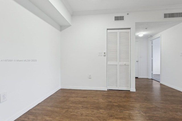 unfurnished room featuring crown molding, dark hardwood / wood-style flooring, and a textured ceiling