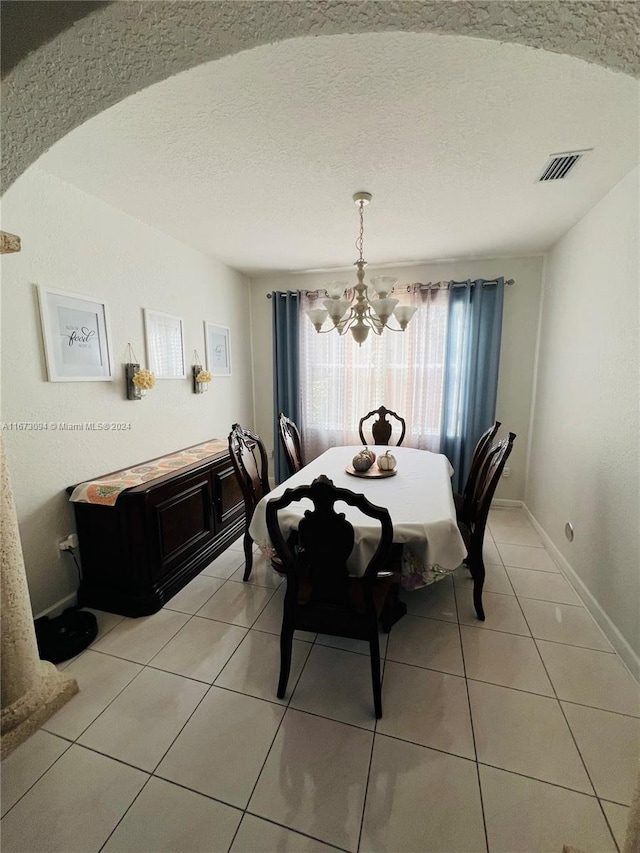 tiled dining space featuring an inviting chandelier and a textured ceiling