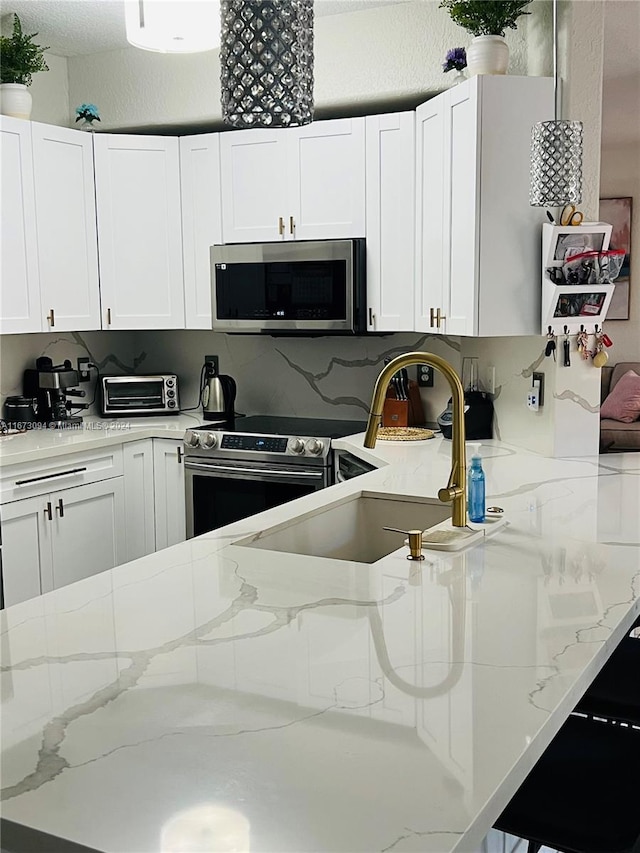 kitchen with stainless steel appliances, sink, white cabinets, light stone counters, and tasteful backsplash