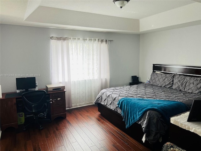 bedroom featuring a raised ceiling and dark hardwood / wood-style flooring