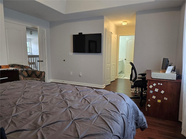 bedroom featuring dark wood-type flooring and ensuite bath