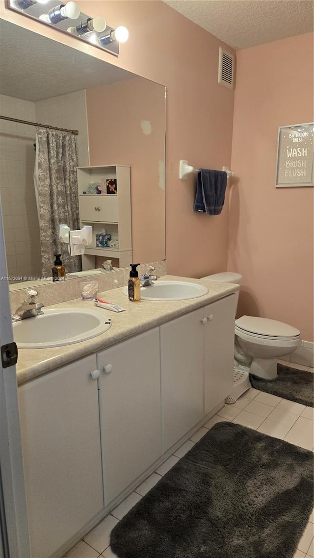 bathroom with vanity, toilet, a textured ceiling, and tile patterned flooring