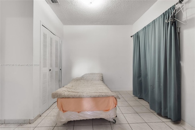 bedroom with a closet, light tile patterned flooring, and a textured ceiling