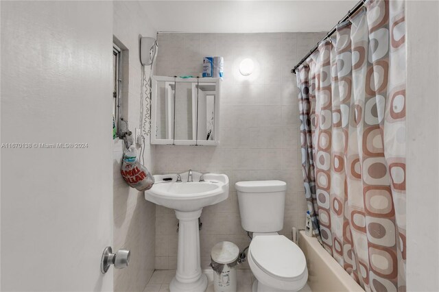 bathroom featuring tile walls, shower / tub combo, and toilet