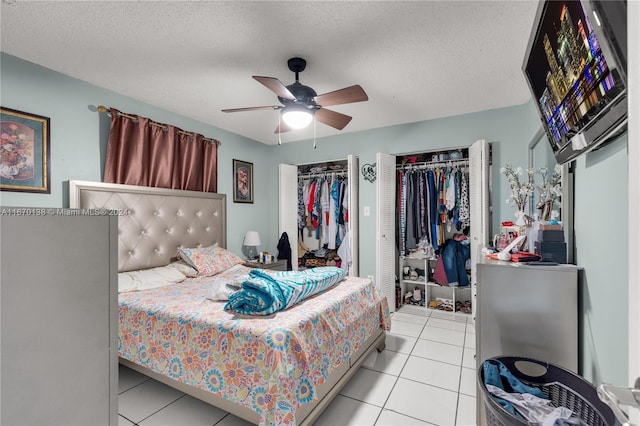 tiled bedroom with ceiling fan, multiple closets, and a textured ceiling