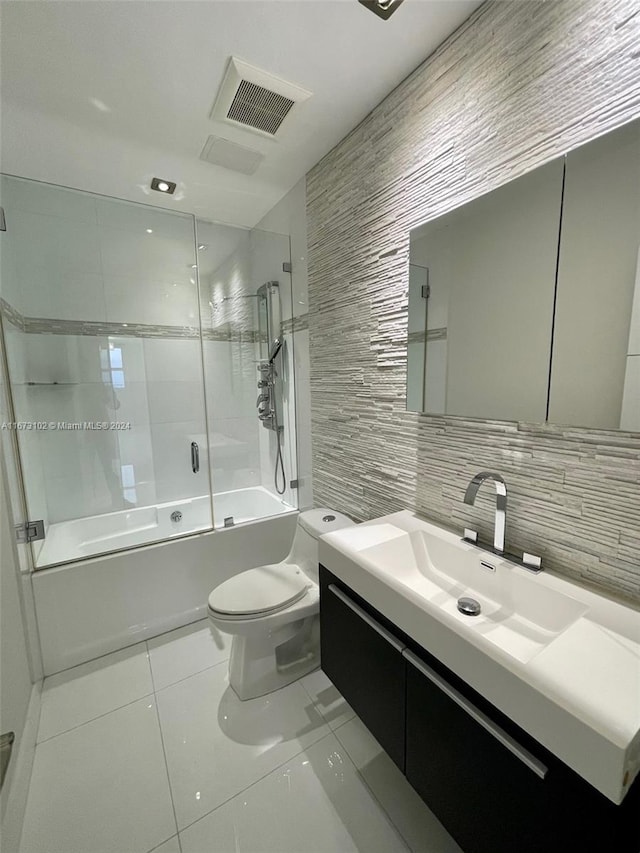 full bathroom featuring tile walls, backsplash, vanity, combined bath / shower with glass door, and toilet