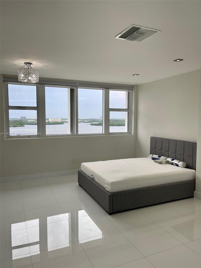 bedroom featuring a water view and light tile patterned floors