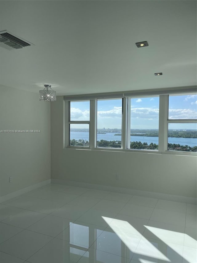 spare room featuring tile patterned flooring and a water view