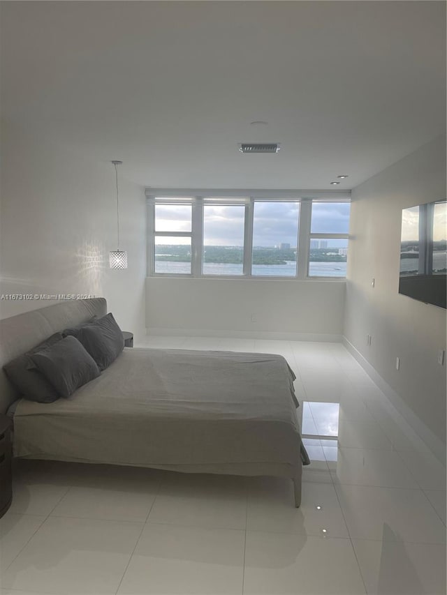 tiled bedroom featuring an inviting chandelier and a water view