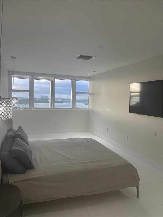 bedroom featuring a water view and light tile patterned flooring