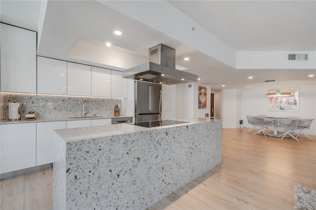 kitchen featuring white cabinets, sink, island range hood, high end fridge, and light hardwood / wood-style flooring