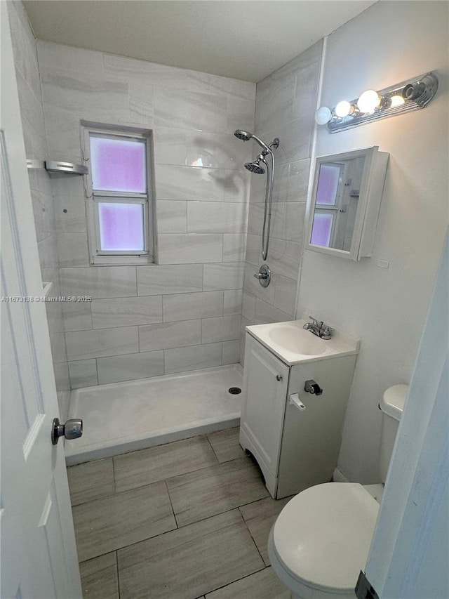 bathroom featuring vanity, toilet, and a tile shower