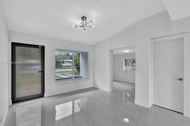 empty room with a chandelier and vaulted ceiling