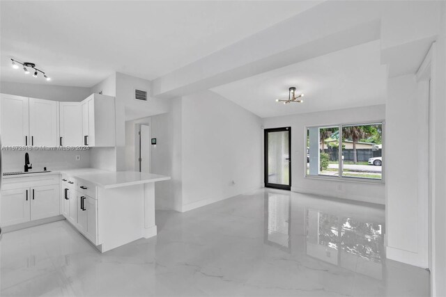 kitchen with sink, a chandelier, white cabinets, and kitchen peninsula