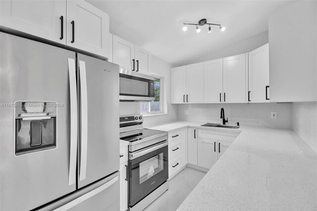 kitchen featuring decorative backsplash, stainless steel appliances, sink, light stone countertops, and white cabinetry