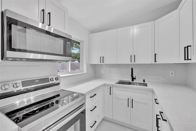 kitchen with appliances with stainless steel finishes, sink, and white cabinets