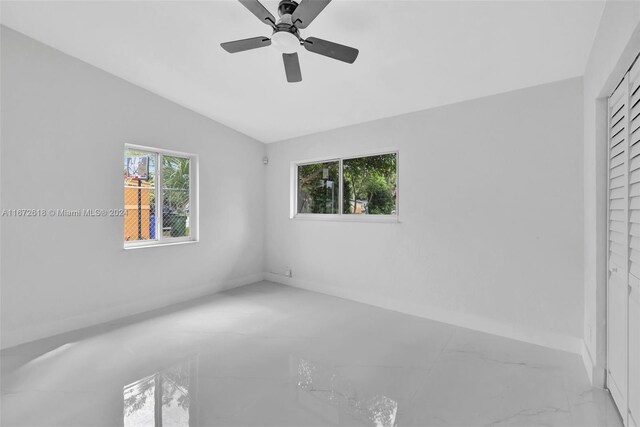 unfurnished bedroom featuring lofted ceiling, a closet, and ceiling fan